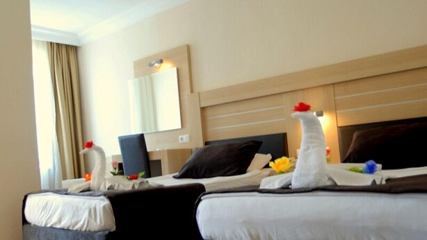 A hotel room with two beds, a large mirror, and a desk with a chair. - Best House Hotel (Alanya)