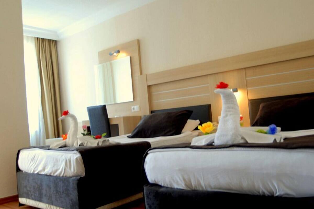 A hotel room with two beds, a large mirror, and a desk with a chair.