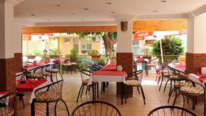 An outdoor dining area with tables and chairs, a brick wall, and a view of the street. - Best House Hotel (Alanya)
