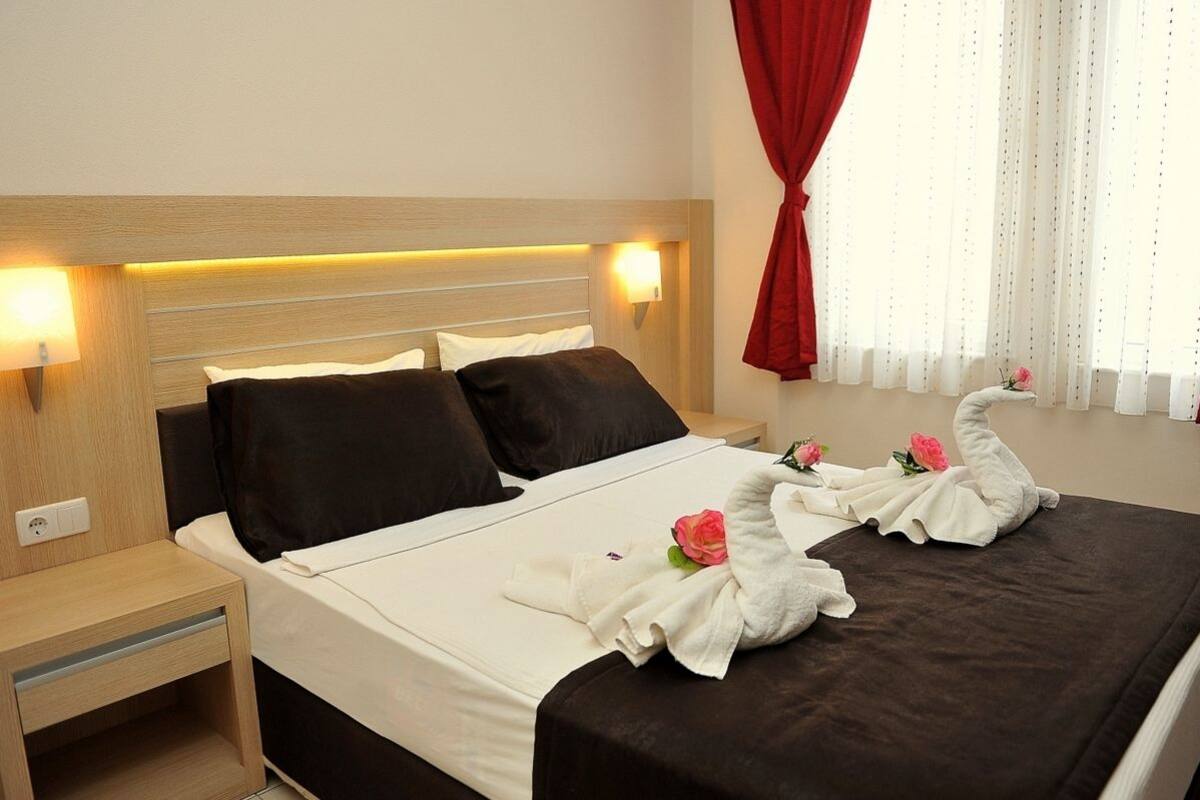 A hotel room with a bed, bedside tables, and a window with curtains.