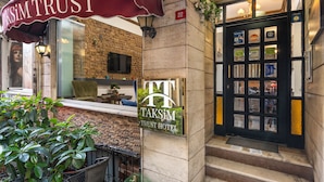 A hotel entrance with a sign reading "TAKSIM TRUST HOTEL," a brick wall, and a black door with glass panels. - Taksim Trust Hotel (Istanbul)