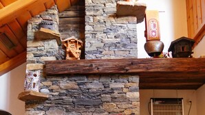 Una chimenea de piedra con repisa, techo de madera y decoración rústica.