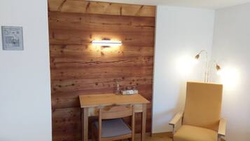 Una habitación pequeña con una pared de madera, una mesa con una silla y una lámpara.
