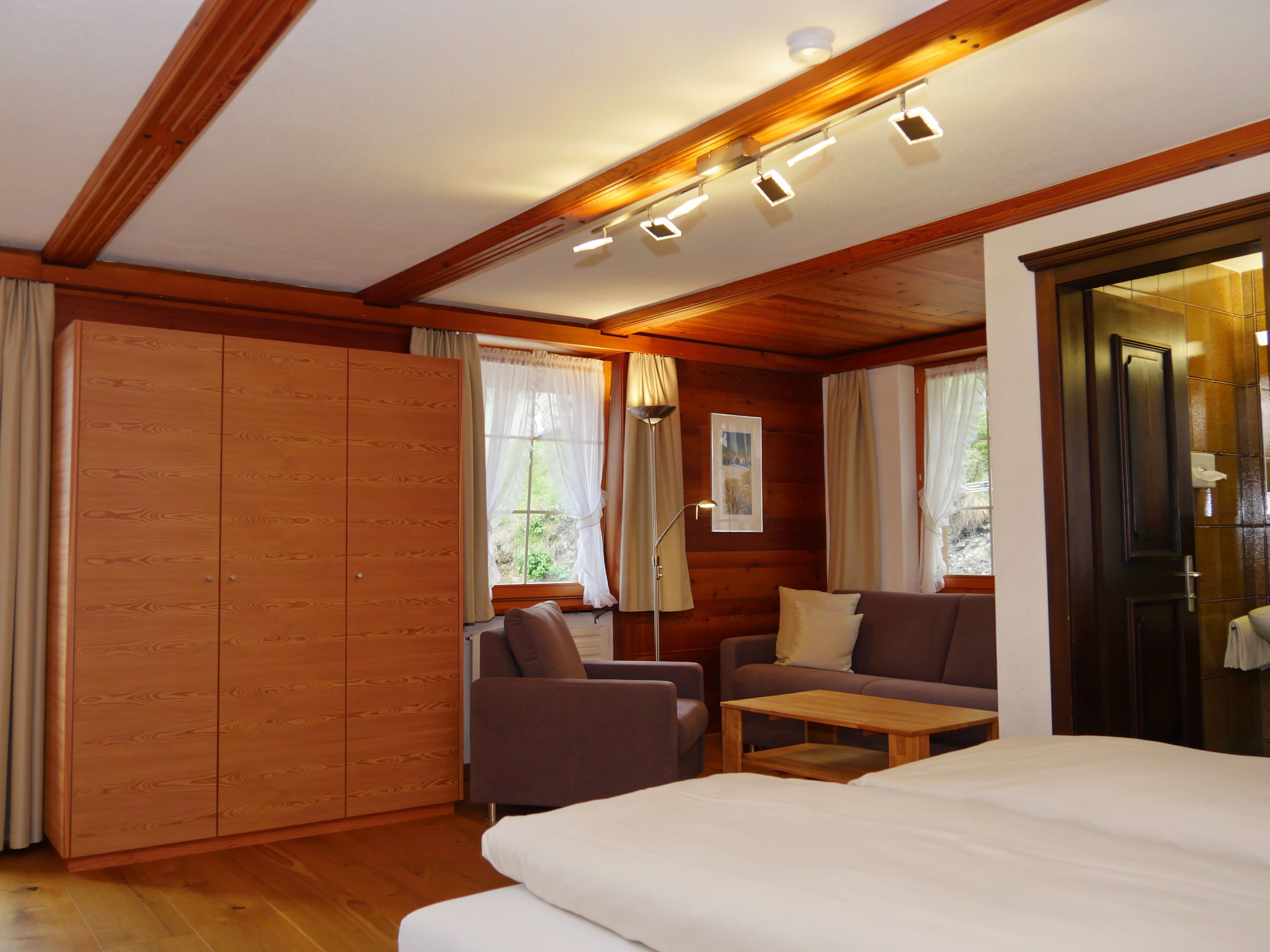 Una habitación con cama, sofá, una mesita y un armario.