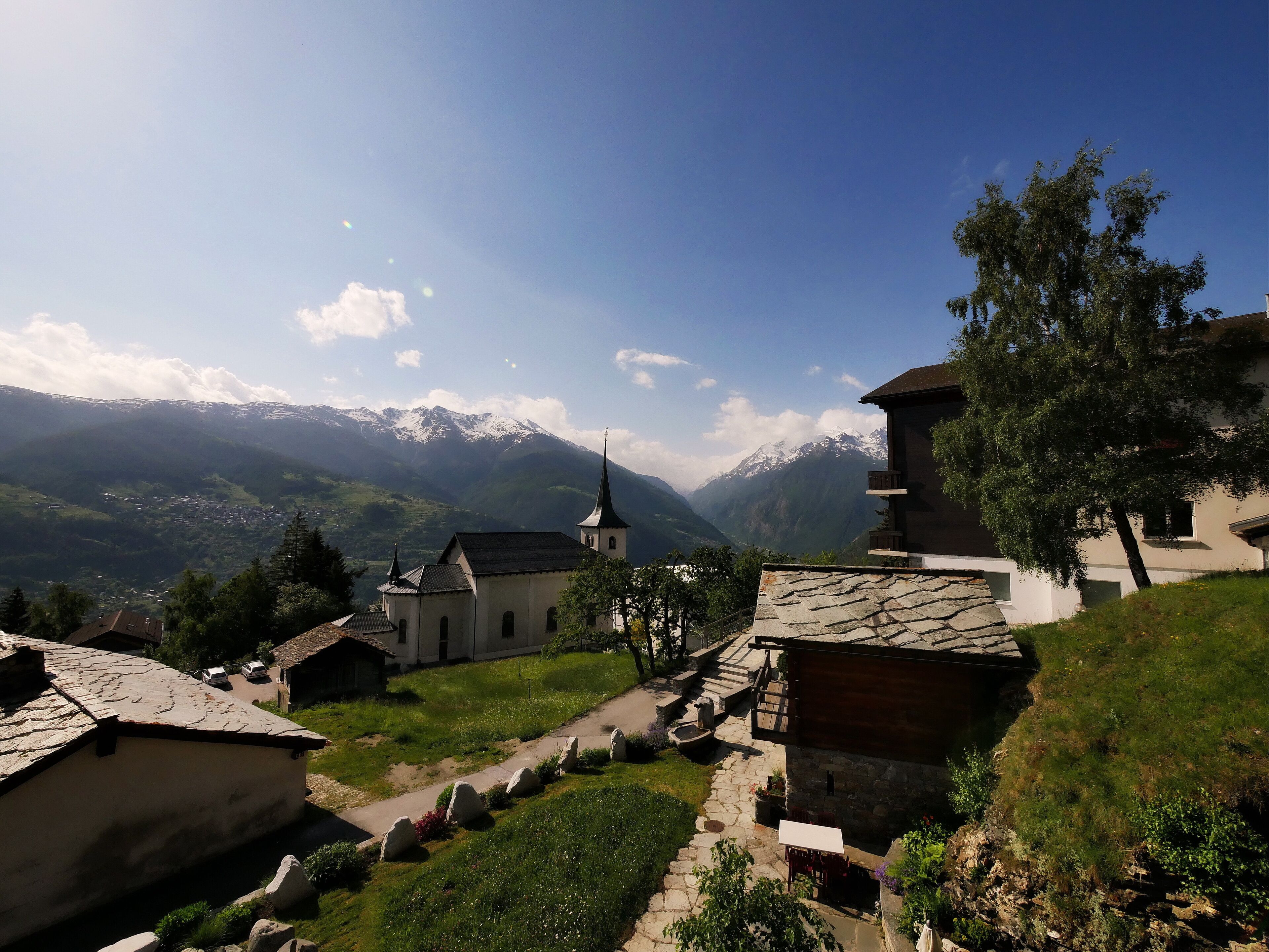 A traditional village with stone buildings, a church, and a mountain backdrop.