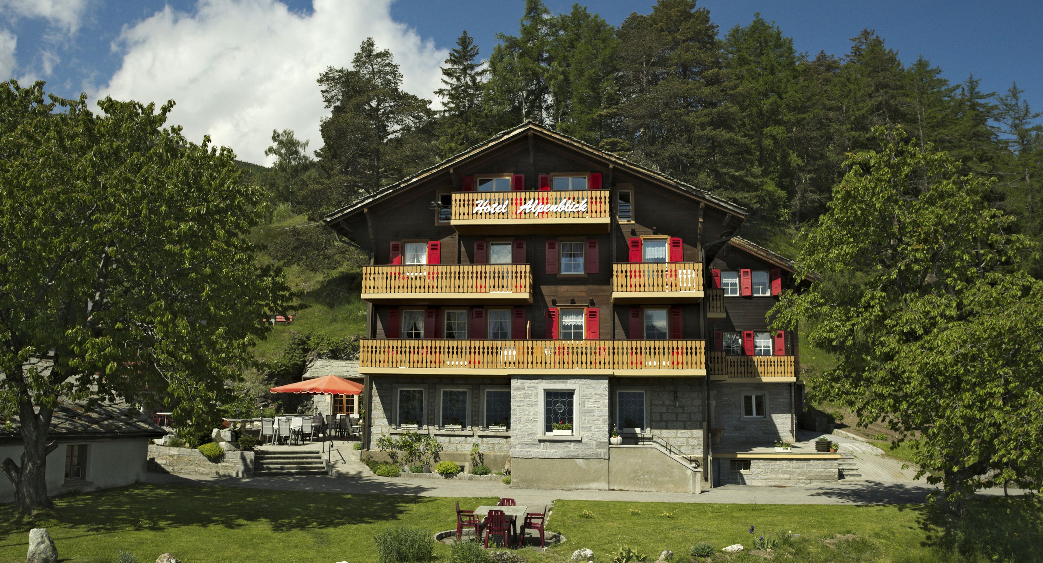 Un hotel a più piani con balconi, facciata in pietra e una zona giardino.