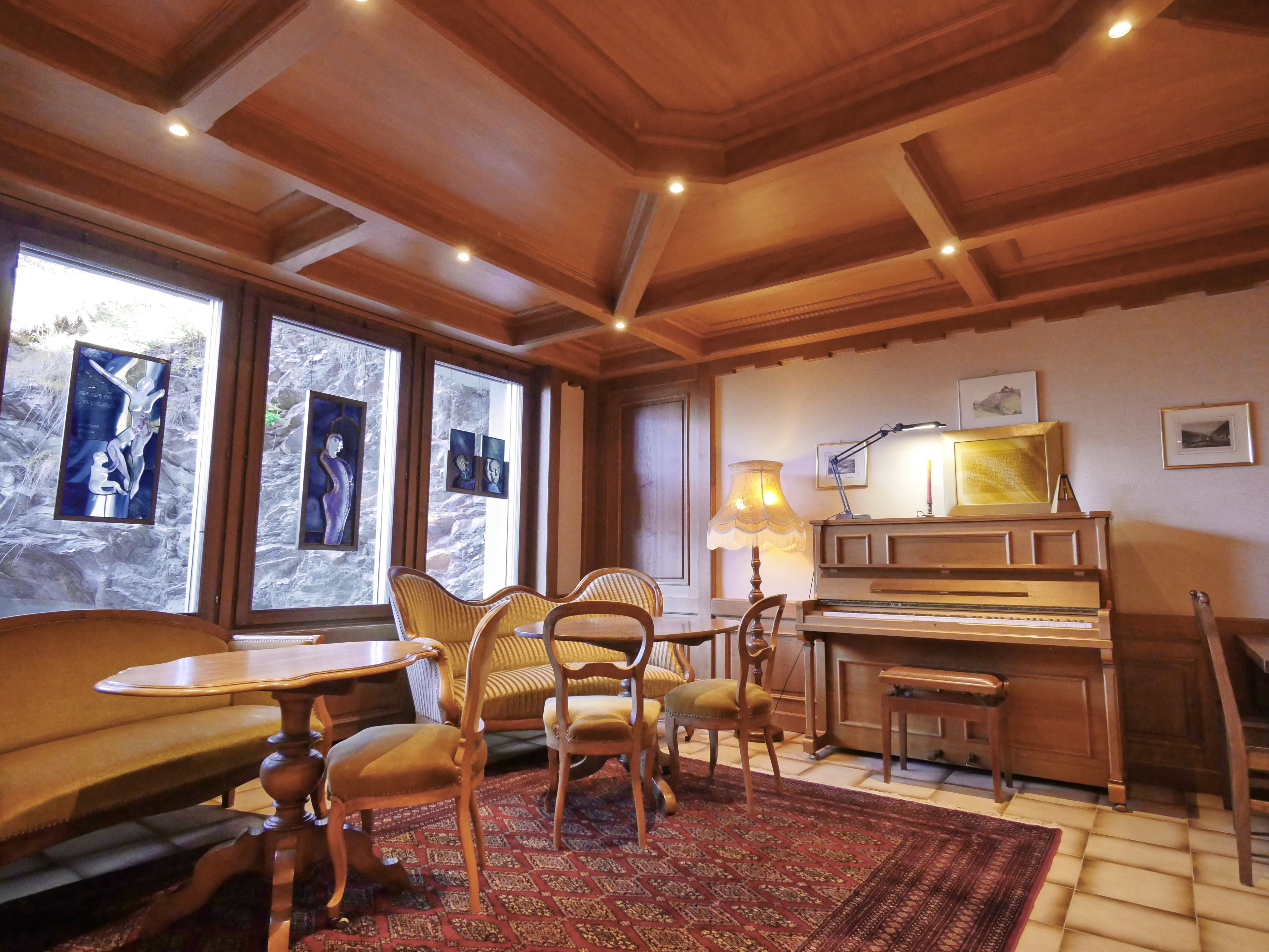 A cozy room with a piano, wooden furniture, and artwork on the walls.