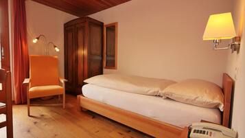 Una camera da letto con un letto di legno, una sedia, un comodino con una lampada e un telefono.