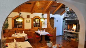 Un restaurante acogedor con cabinas de madera, chimenea de piedra y candelabros colgantes.