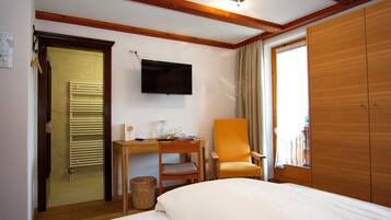 A hotel room with a bed, a desk, a chair, a television, and a wardrobe.