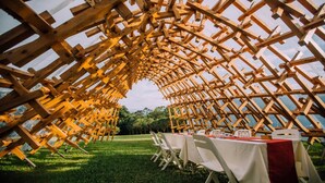 An outdoor wooden structure with tables set up for dining, surrounded by a grassy area. - The One Nanyuan (Xinpu)