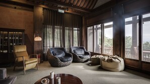 A cozy lounge area with a brick wall, large windows, and comfortable seating including a sofa and two armchairs. - The One Nanyuan (Xinpu)