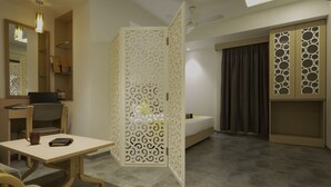 A hotel room with a desk, chair, bed, and wardrobe. - Hotel Sifat International (Surat)