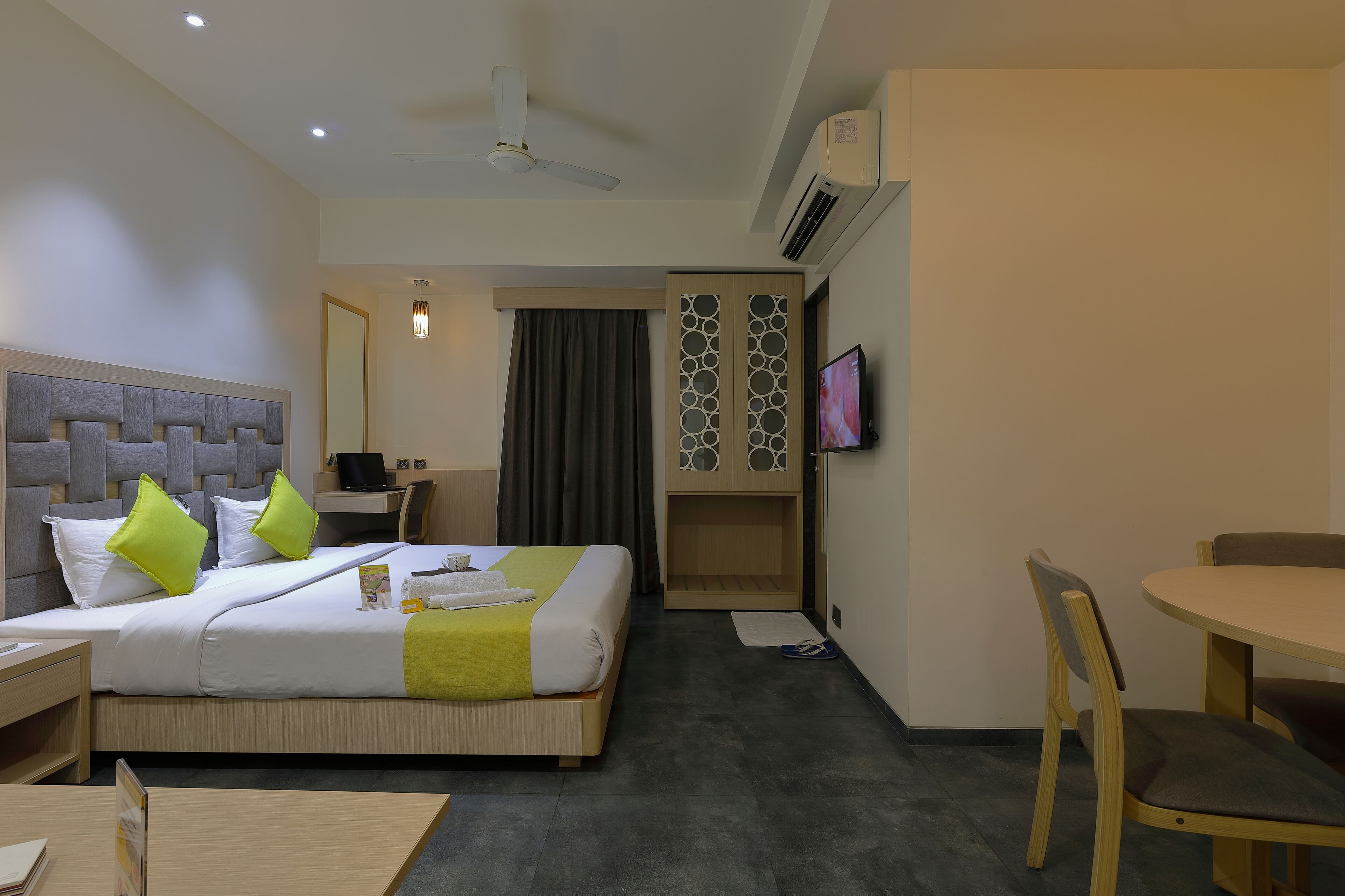 Una habitación de hotel con cama, escritorio, silla, televisor y una mesita.