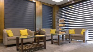 A modern living room with two sofas, each with a glass coffee table and yellow cushions. - Hotel Sifat International (Surat)