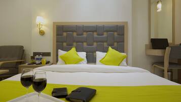 Une chambre d’hôtel avec un lit, une table de chevet, une lampe et une chaise.