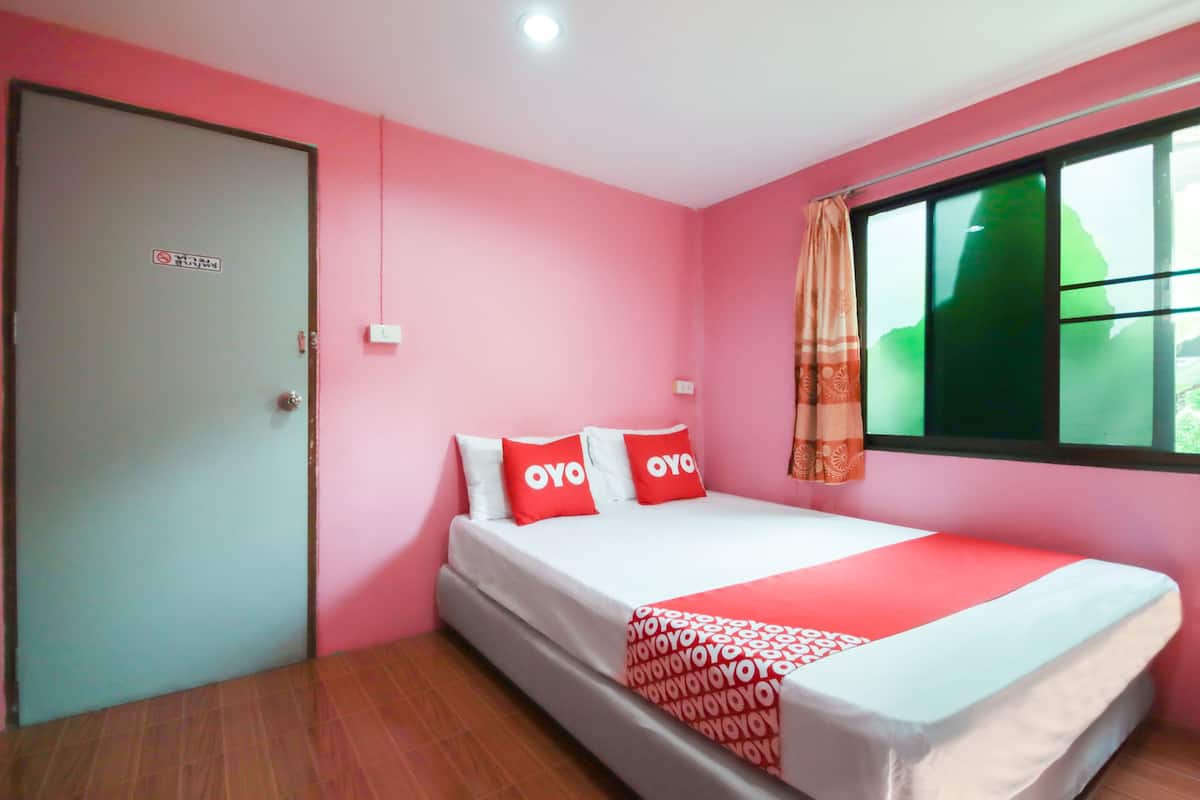 A room with a bed, a door, and a window with a curtain.