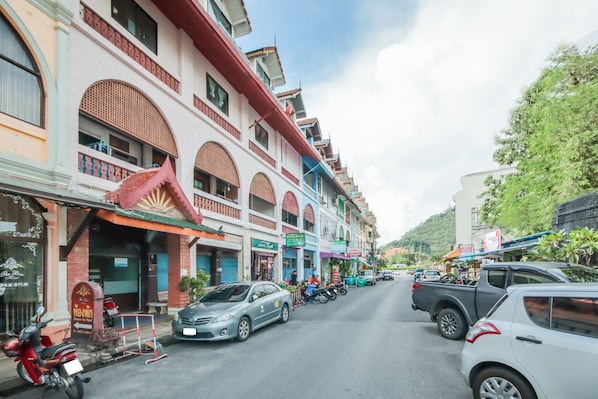 A street view with buildings featuring traditional architecture, a parked car, and a motorcycle.