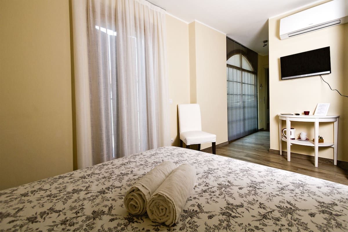 Ein Hotelzimmer mit einem Bett, einem Sessel, einem kleinen Tisch mit einer Tasse und einem Fenster.