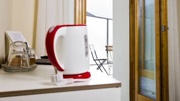 Un coin cuisine avec une machine à café rouge et blanche, un bocal en verre et un panneau indiquant le menu.