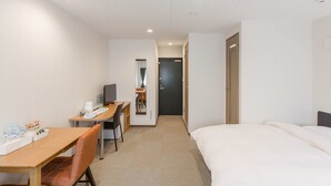 A hotel room with a bed, a desk with a chair, a television, and a bathroom visible through an open door. - Guest House & Hotel Shijo Omiya (Kyoto)