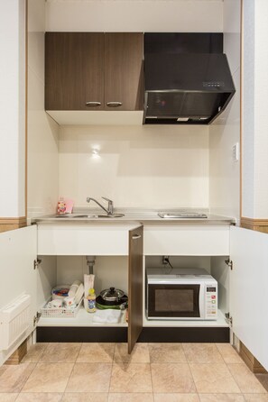 Een koelkast, een magnetron, een oven, kookgerei, borden en bestek