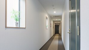 A hallway with a plant, framed pictures, and a door. - Guest House & Hotel Shijo Omiya (Kyoto)