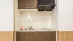 A compact kitchen with wooden cabinets, a stainless steel sink, and a black range hood. - Guest House & Hotel Shijo Omiya (Kyoto)
