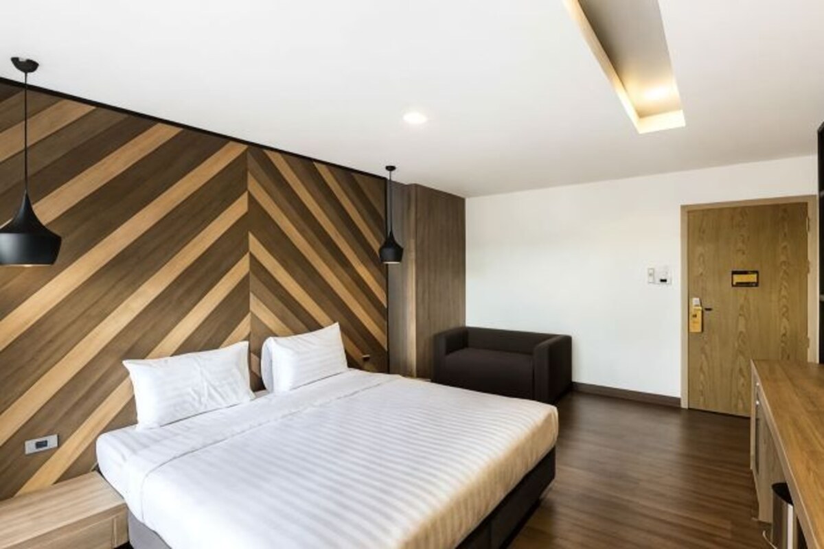 Een moderne hotelkamer met een groot bed, een bureau en een stoel.