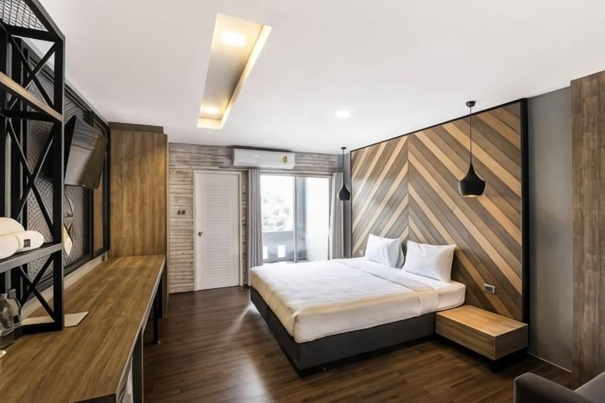 A modern bedroom with a bed, bedside table, and a desk with a chair.
