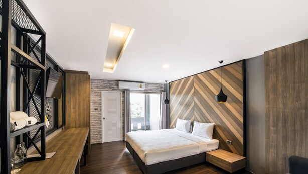 A modern bedroom with a bed, bedside tables, a built-in bench, a desk, and a shelving unit. - The Circle Hotel (Buriram)