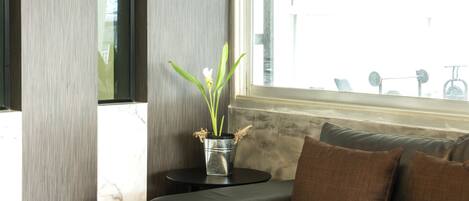 A modern living room with a dark leather sofa, a small round table, and a potted plant.
