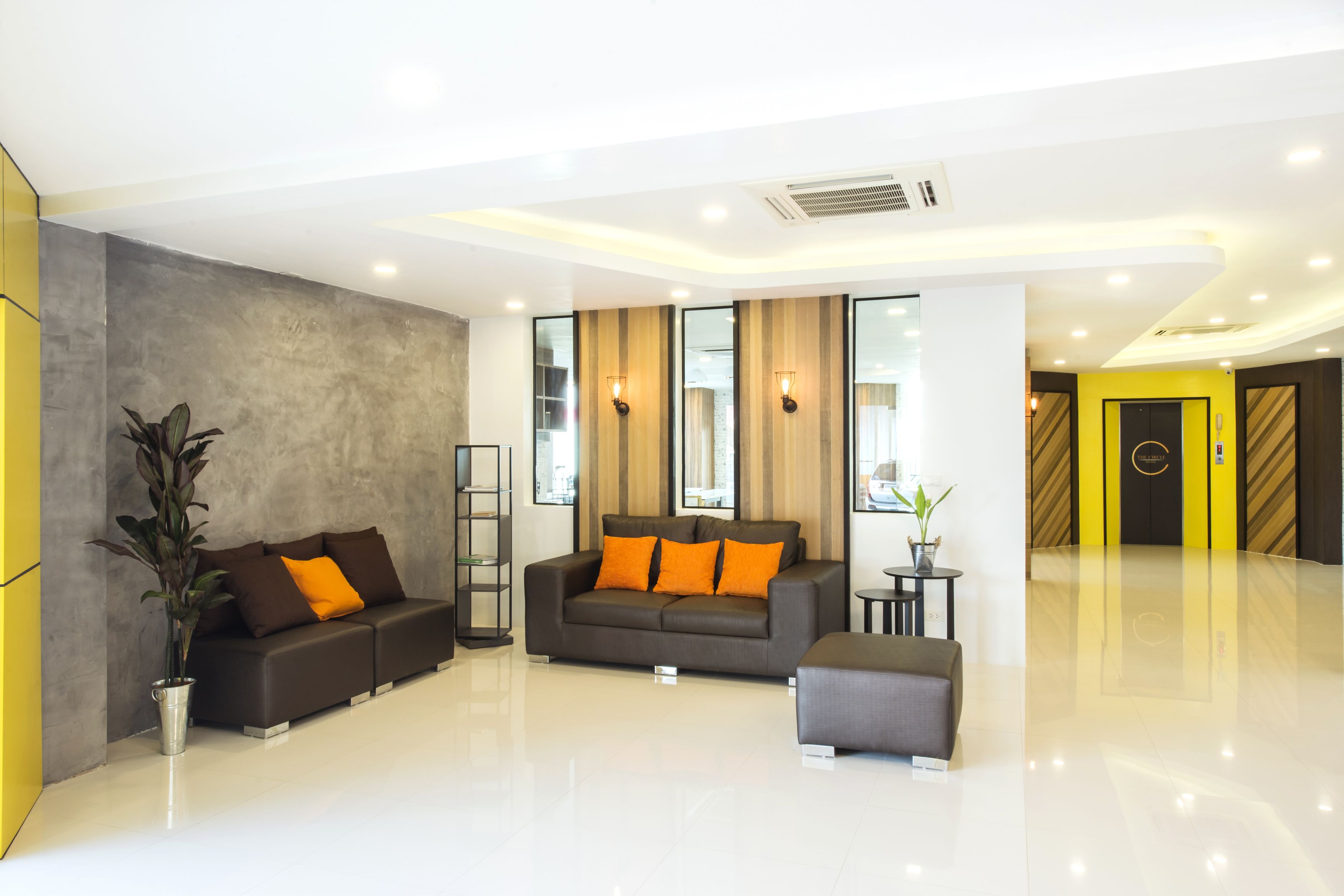 A modern lobby with a grey sofa set, a small table, and a potted plant.