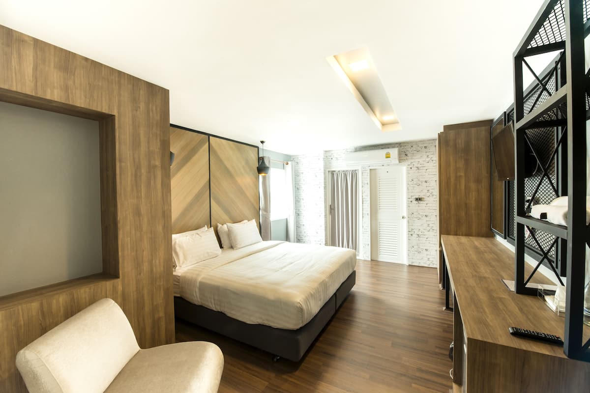 A modern bedroom with a large bed, a desk, and a shelving unit.