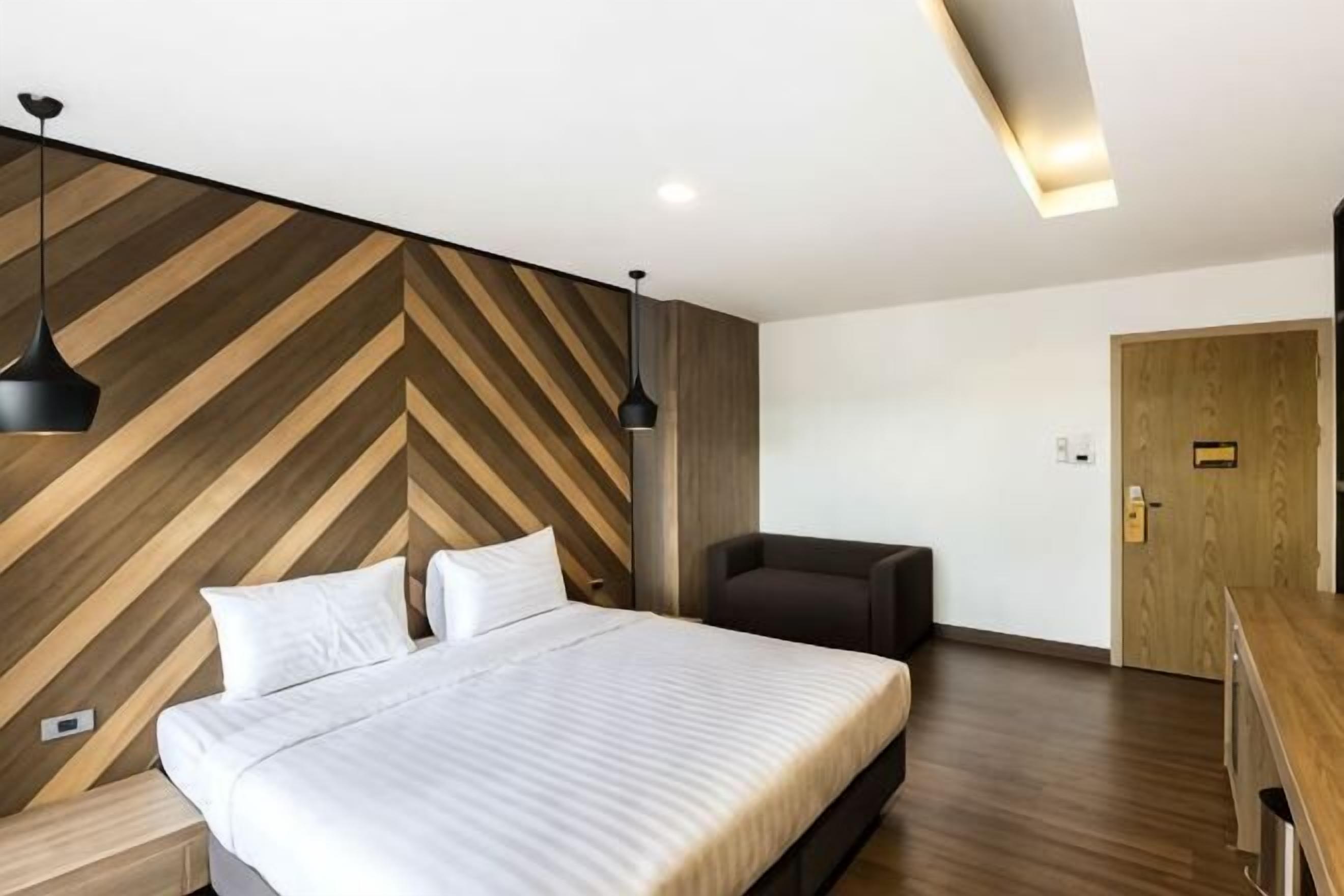 Una habitación de hotel moderna con una cama grande, un escritorio y una silla.
