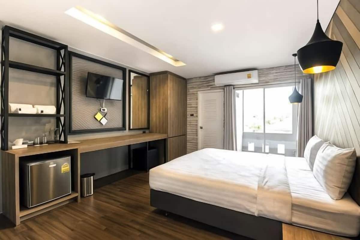 A modern bedroom with a bed, built-in TV, and a desk with a computer.