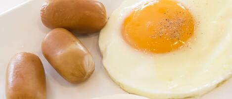 A white plate with two sunny-side-up eggs and three sausages.