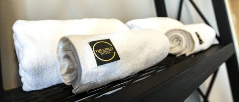 Three neatly folded white towels with a logo on a black shelf.