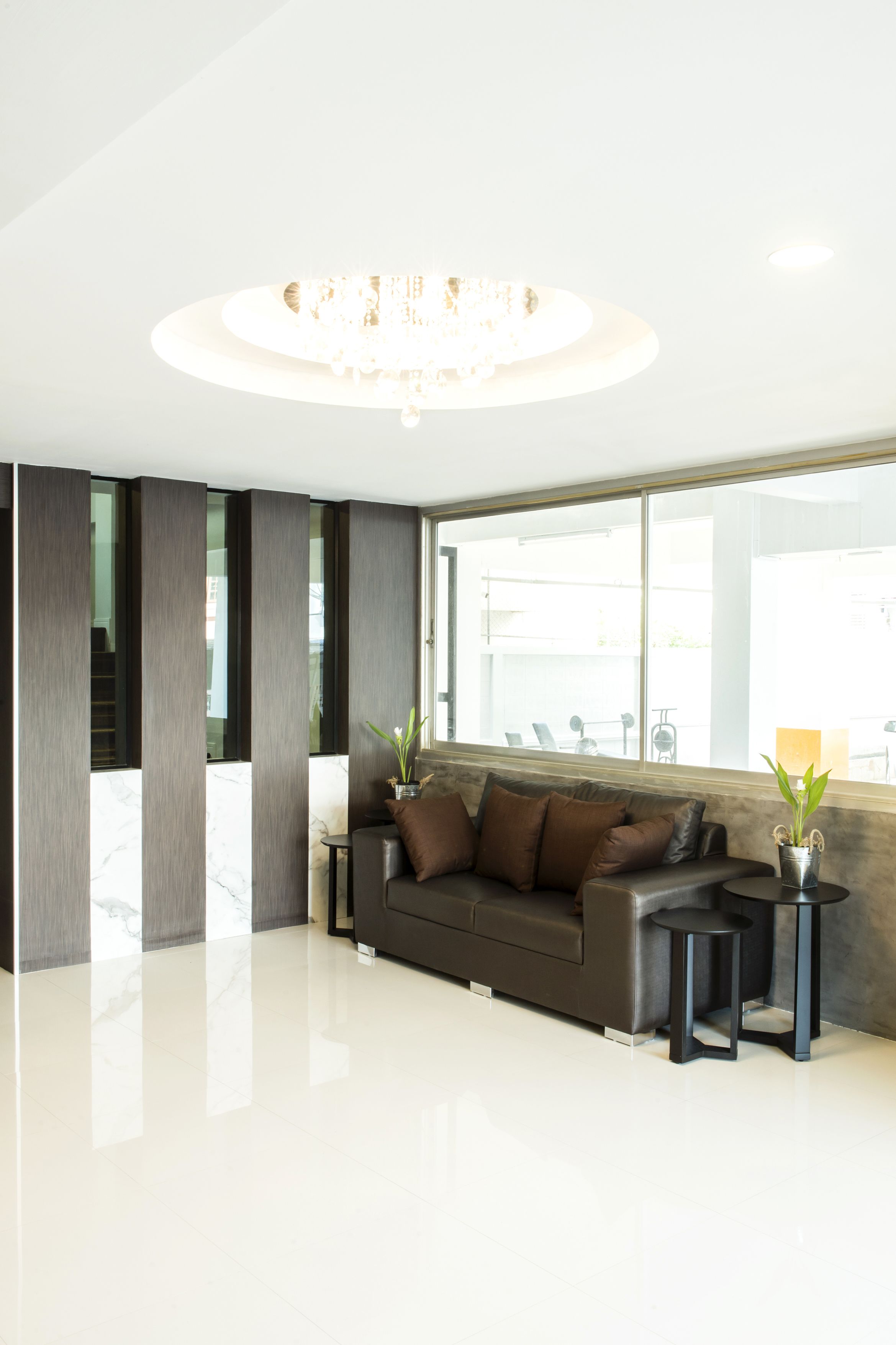 Una sala de estar moderna con un sofá de cuero oscuro, dos mesitas auxiliares y un ventanal con vistas al exterior.