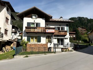 A multi-story building with balconies, a sign for 'Giustina', and a mountain backdrop. - Meublè Bar Giustina (Auronzo di Cadore)