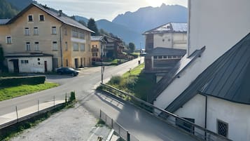Eine Wohnstraße mit Häusern, einem Auto und Bergen im Hintergrund.