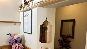A staircase with a wooden handrail, a wall-mounted clock, a framed abstract painting, a decorative angel, a 'no smoking' sign, and a mirror. - Meublè Bar Giustina (Auronzo di Cadore)