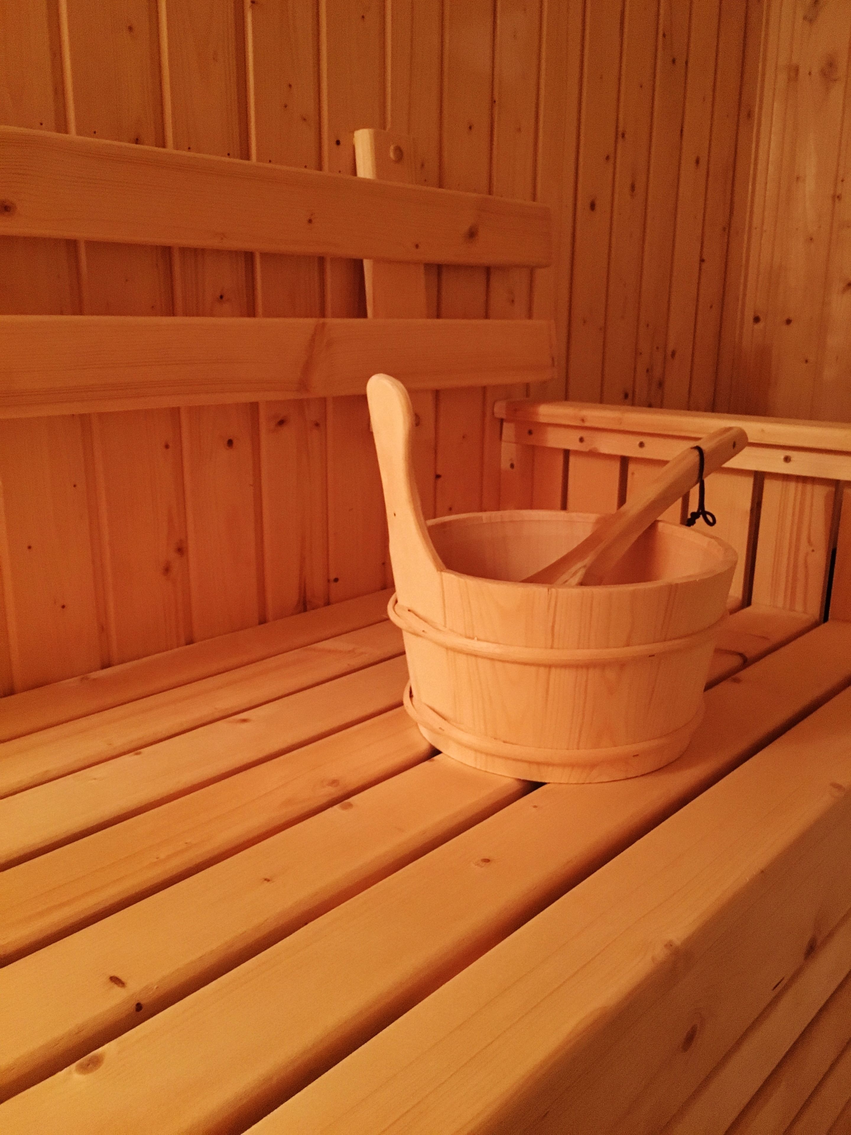 Eine Holzsauna mit einer Holzbänke und einem Holzfass mit einem Holzhammer.