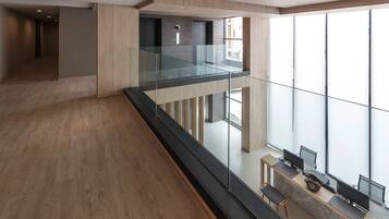 A modern interior with a glass railing, a wooden floor, and a desk with computers.