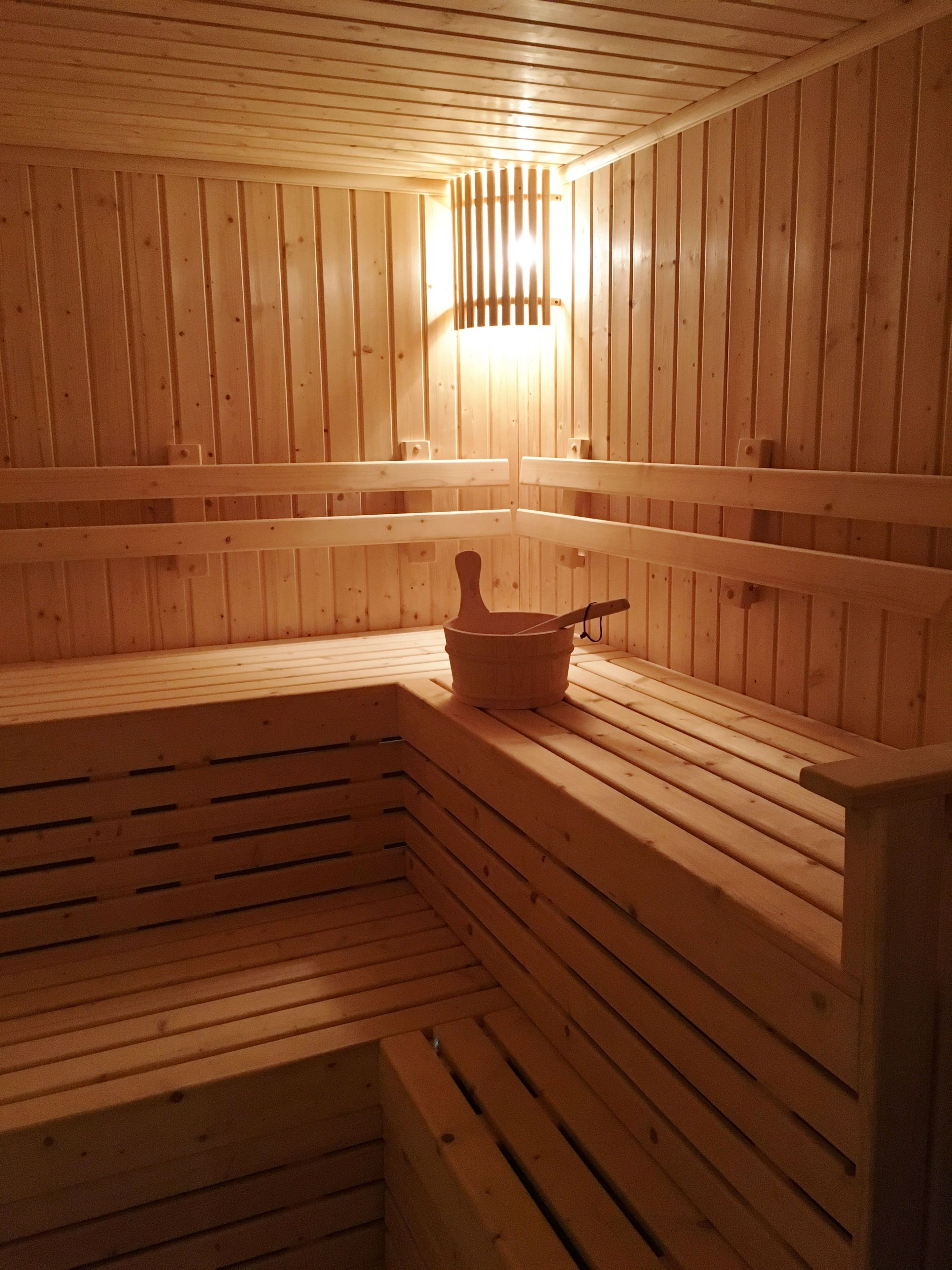 Una sauna con bancos de madera y un cubo de madera.