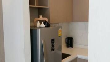 A compact kitchen with a refrigerator, a coffee maker, and a microwave.