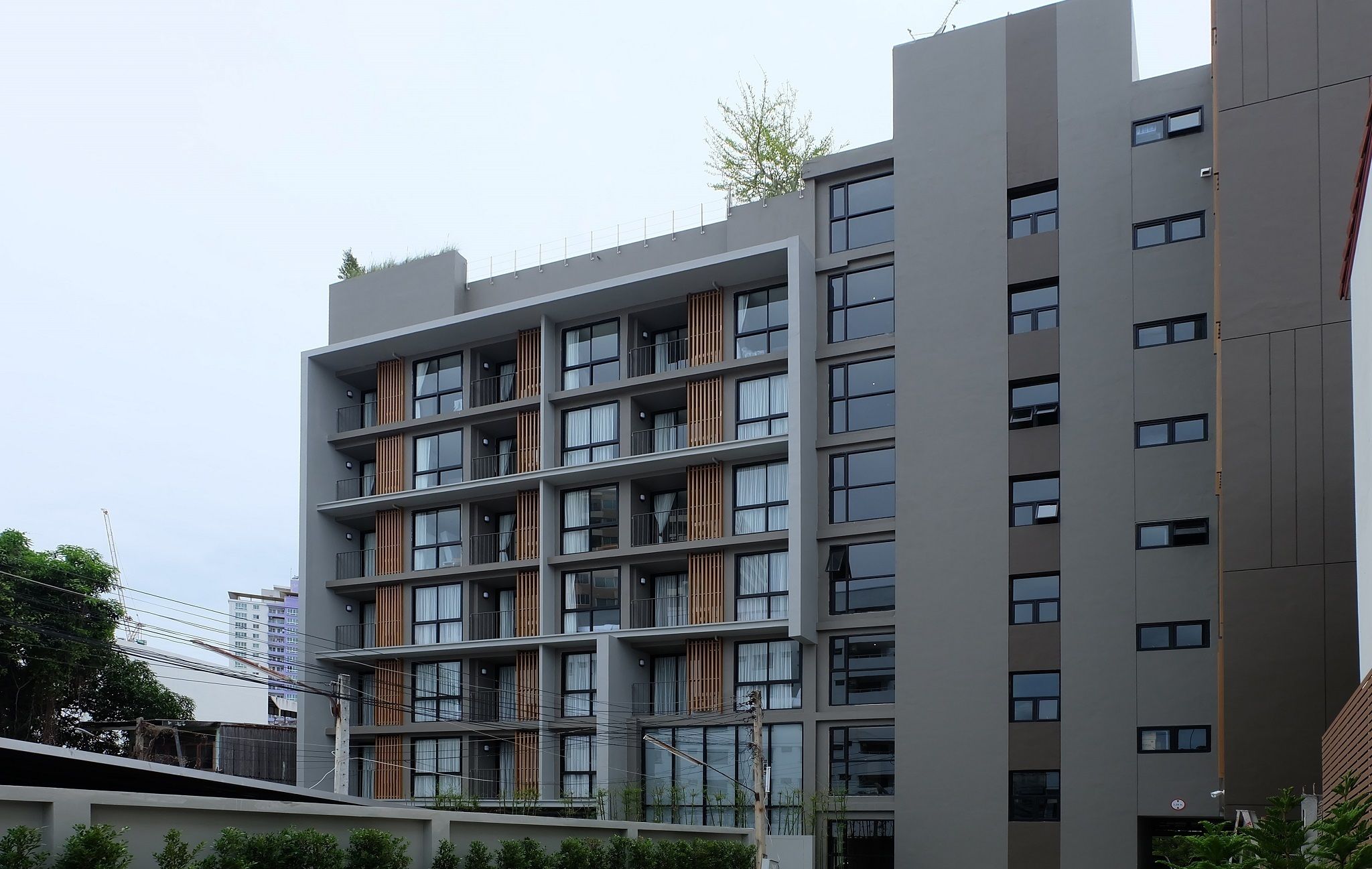 A multi-story building with a modern architectural design, featuring balconies with railings and large windows.