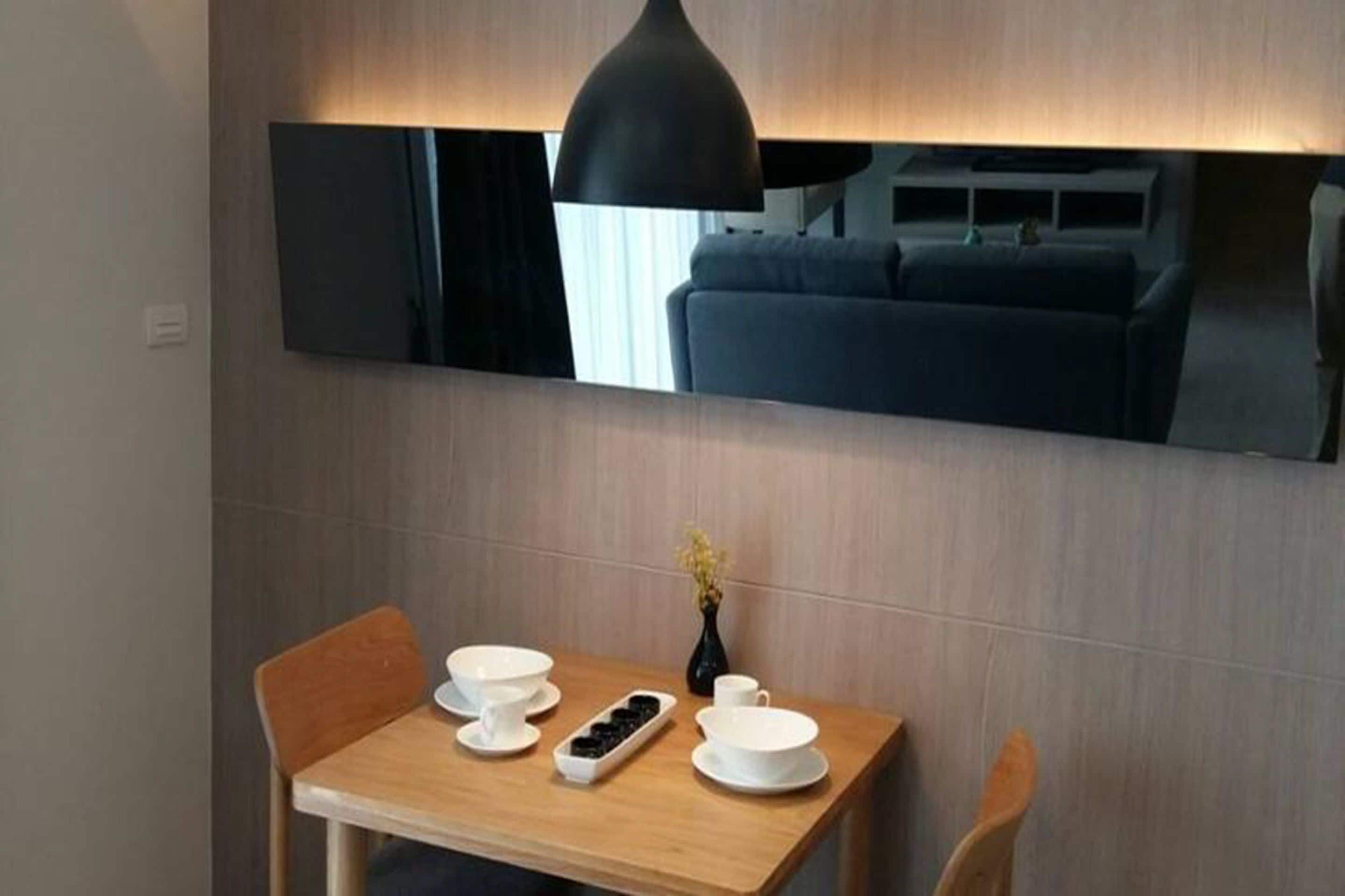 A modern dining area with a wooden table, white bowls, and a black pendant light.
