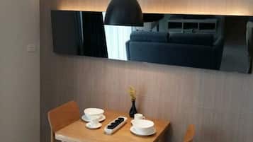 A modern dining area with a wooden table, white bowls, and a black pendant light.
