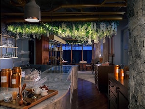 A modern bar area with a marble countertop, shelves with glassware, and a hanging green plant decoration. - Madera Residence Siracha (Si Racha)